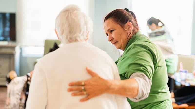 Staff member escorting senior woman with hand on her back